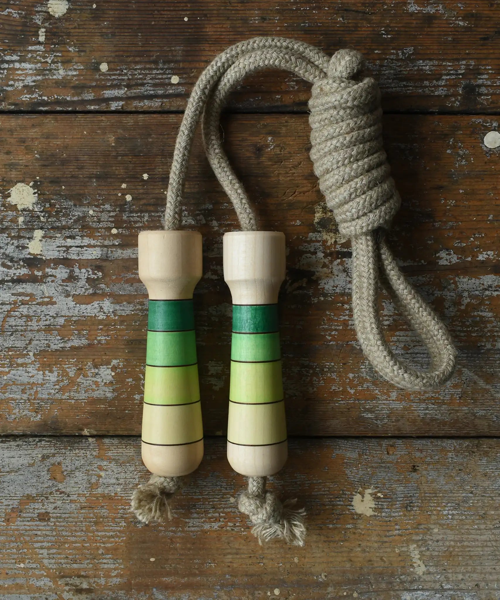 Mader Kreiselmanufaktur Skipping Rope with green striped wooden handles placed on a wooden board in the Bbaipur playroom.