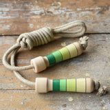 Mader Kreiselmanufaktur Skipping Rope with green striped wooden handles placed on a wooden board in the Bbaipur playroom.