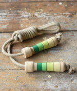 Mader Kreiselmanufaktur Skipping Rope with green striped wooden handles placed on a wooden board in the Bbaipur playroom.