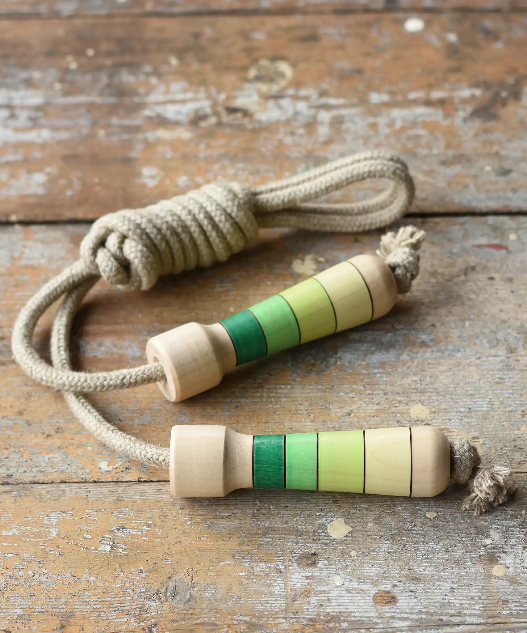 Mader Kreiselmanufaktur Skipping Rope with green striped wooden handles placed on a wooden board in the Bbaipur playroom.