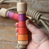 Mader Kreiselmanufaktur Skipping Rope with pink red striped wooden handles placed on a wooden surface in the Babipur playroom. 