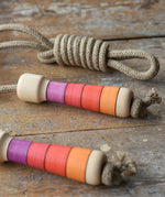 Mader Kreiselmanufaktur Skipping Rope with pink red striped wooden handles placed on a wooden surface in the Babipur playroom. 