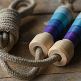 Mader Kreiselmanufaktur Skipping Rope with purple striped wooden handles placed on a wooden surface in the Babipur playroom. 