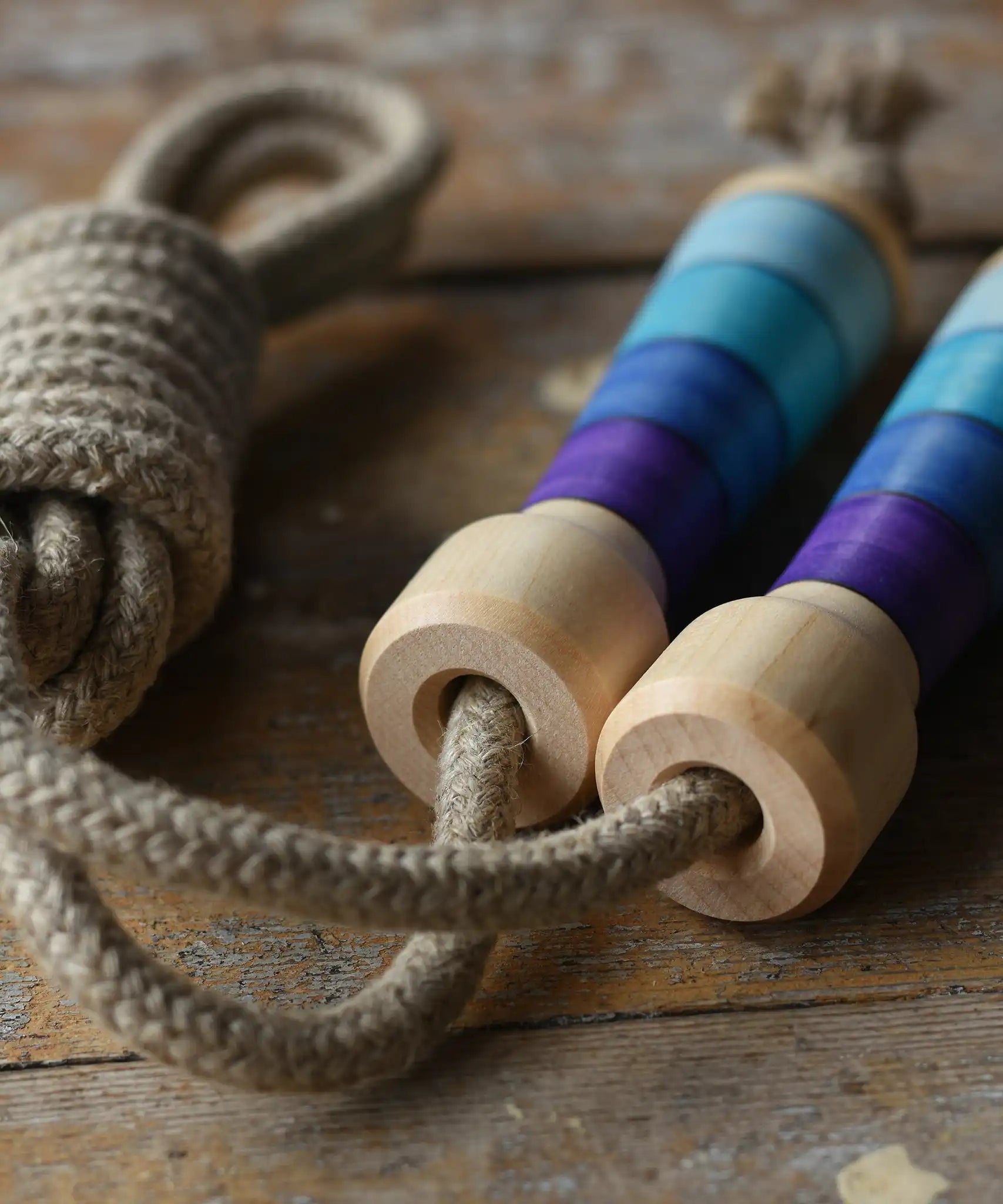 Mader Kreiselmanufaktur Skipping Rope with purple striped wooden handles placed on a wooden surface in the Babipur playroom. 