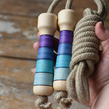 Mader Kreiselmanufaktur Skipping Rope with purple striped wooden handles placed on a wooden surface in the Babipur playroom. 