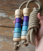 Mader Kreiselmanufaktur Skipping Rope with purple striped wooden handles placed on a wooden surface in the Babipur playroom. 