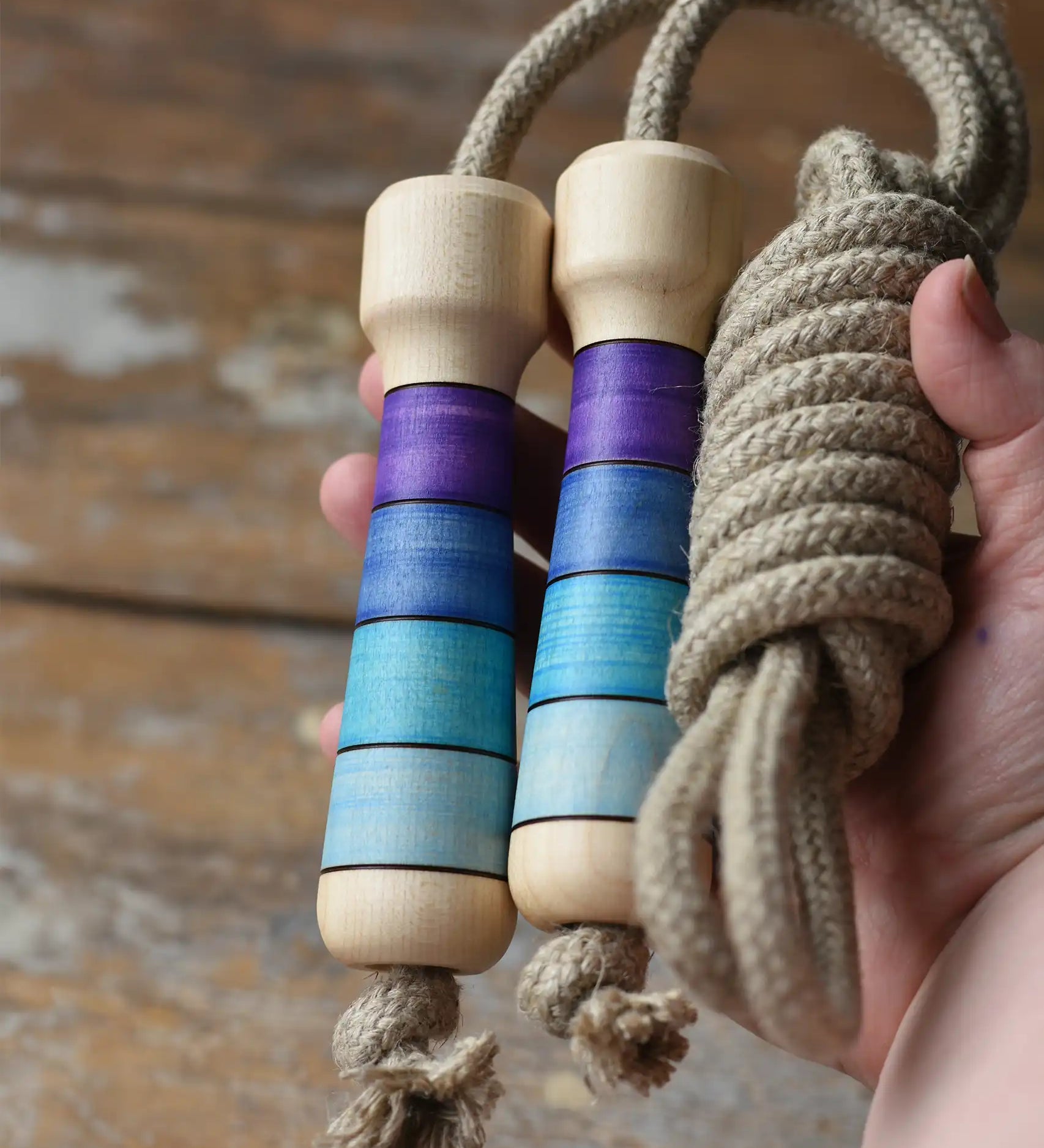 Mader Kreiselmanufaktur Skipping Rope with purple striped wooden handles placed on a wooden surface in the Babipur playroom. 