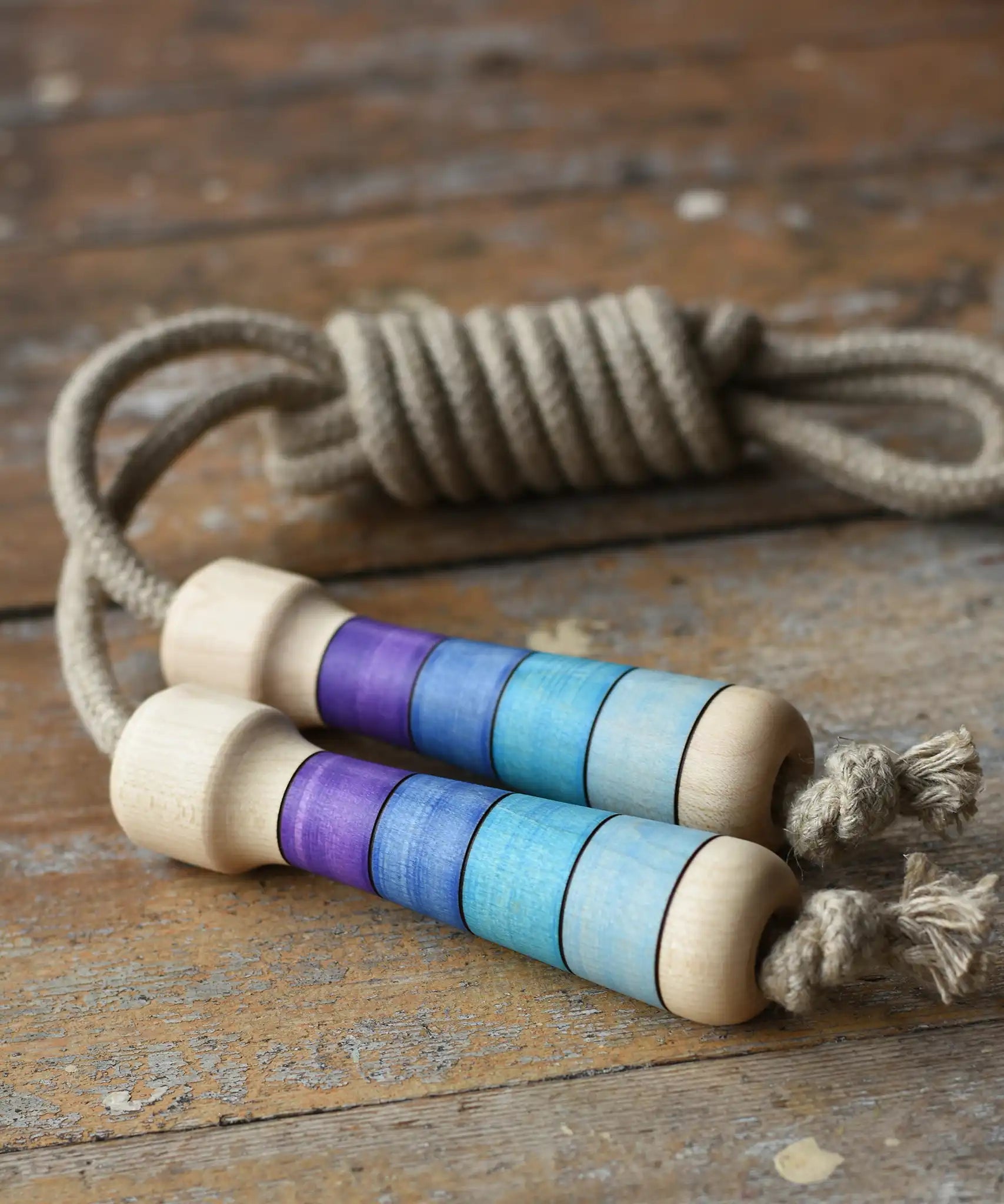 Mader Kreiselmanufaktur Skipping Rope with purple striped wooden handles placed on a wooden surface in the Babipur playroom. 