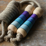 Mader Kreiselmanufaktur Skipping Rope with purple striped wooden handles placed on a wooden surface in the Babipur playroom. 