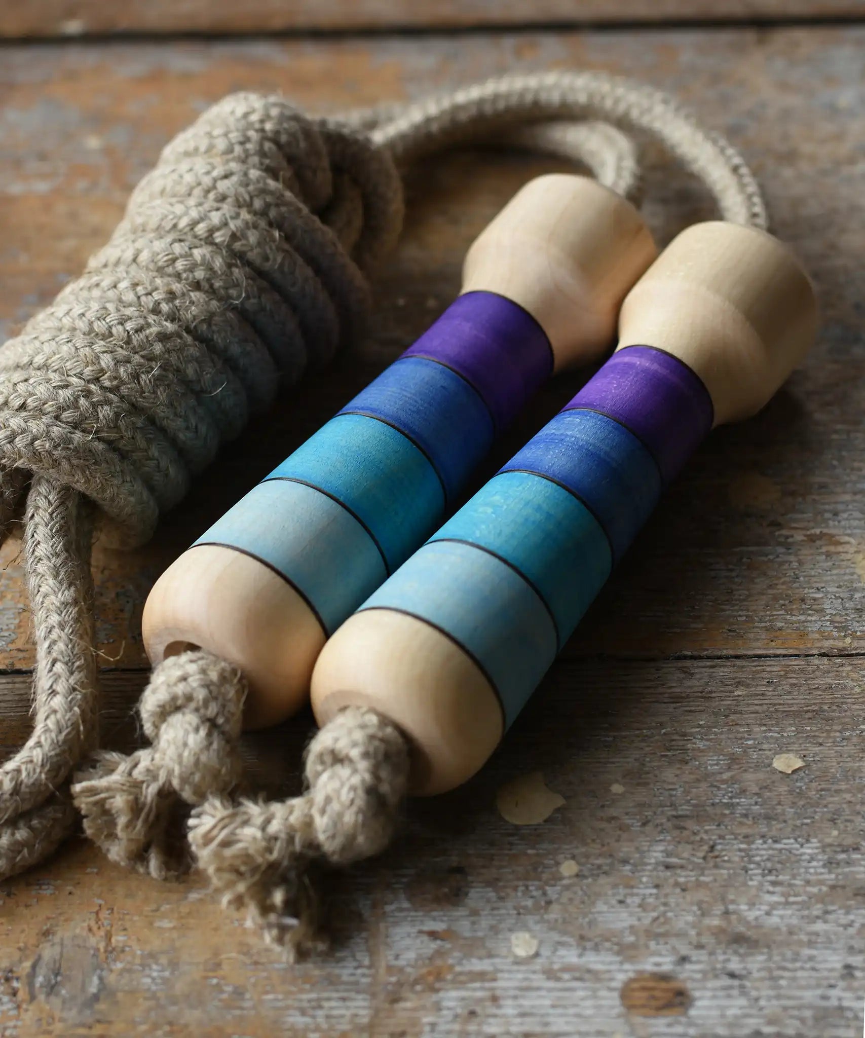Mader Kreiselmanufaktur Skipping Rope with purple striped wooden handles placed on a wooden surface in the Babipur playroom. 