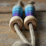 Mader Kreiselmanufaktur Skipping Rope with purple striped wooden handles placed on a wooden surface in the Babipur playroom. 