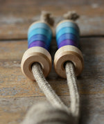 Mader Kreiselmanufaktur Skipping Rope with purple striped wooden handles placed on a wooden surface in the Babipur playroom. 