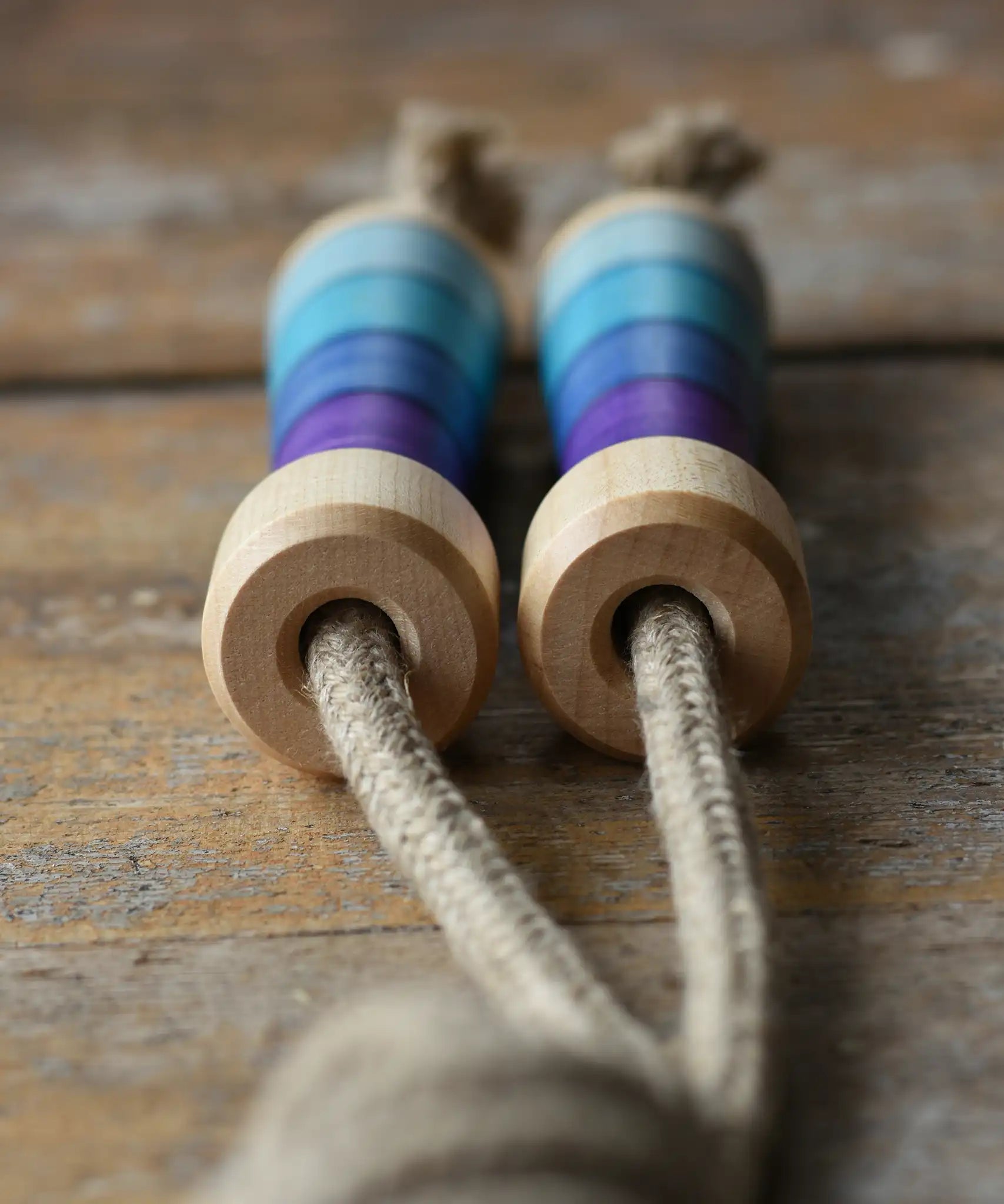 Mader Kreiselmanufaktur Skipping Rope with purple striped wooden handles placed on a wooden surface in the Babipur playroom. 