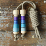 Mader Kreiselmanufaktur Skipping Rope with purple striped wooden handles placed on a wooden surface in the Babipur playroom. 