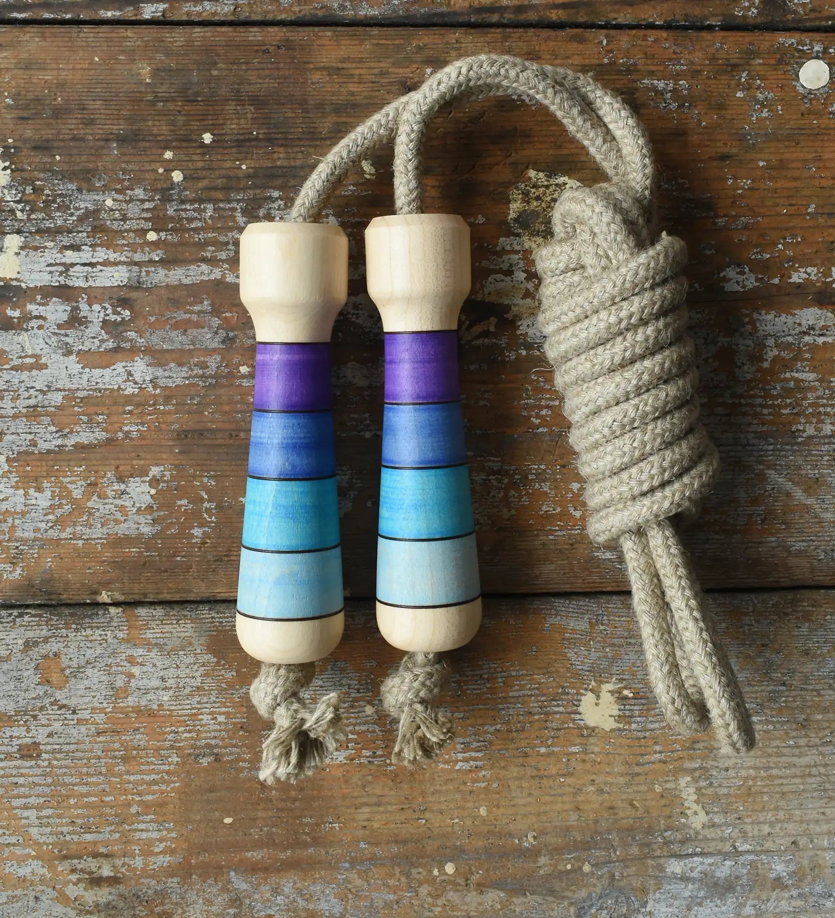 Mader Kreiselmanufaktur Skipping Rope with purple striped wooden handles placed on a wooden surface in the Babipur playroom. 
