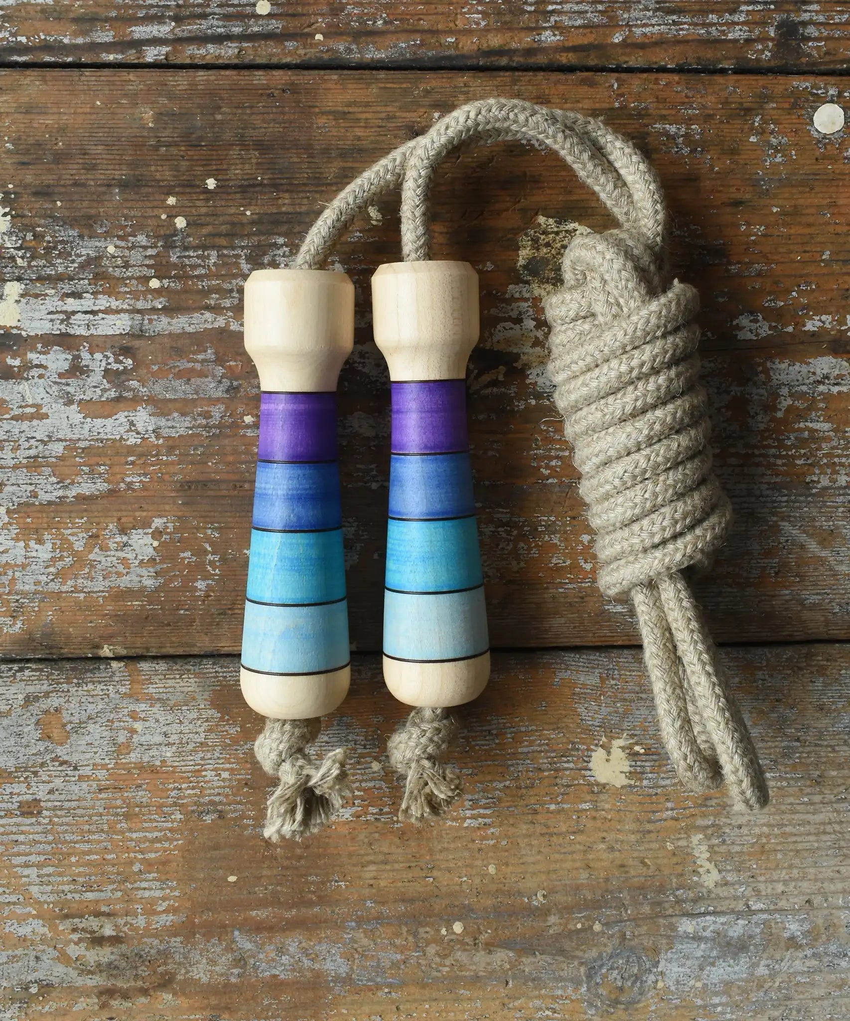 Mader Kreiselmanufaktur Skipping Rope with purple striped wooden handles placed on a wooden surface in the Babipur playroom. 