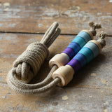 Mader Kreiselmanufaktur Skipping Rope with purple striped wooden handles placed on a wooden surface in the Babipur playroom. 