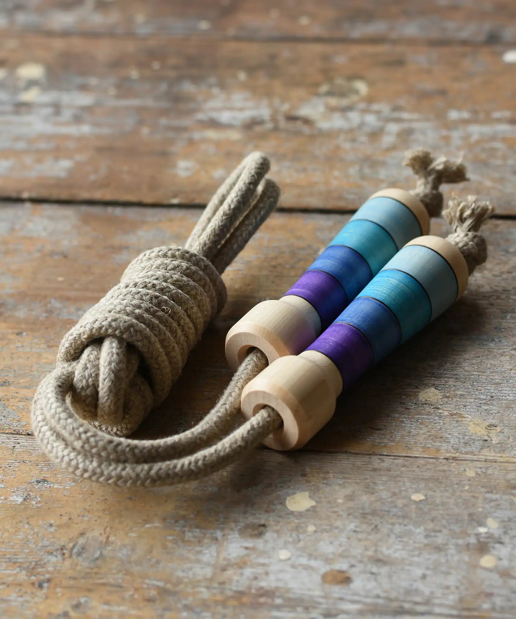 Mader Kreiselmanufaktur Skipping Rope with purple striped wooden handles placed on a wooden surface in the Babipur playroom. 