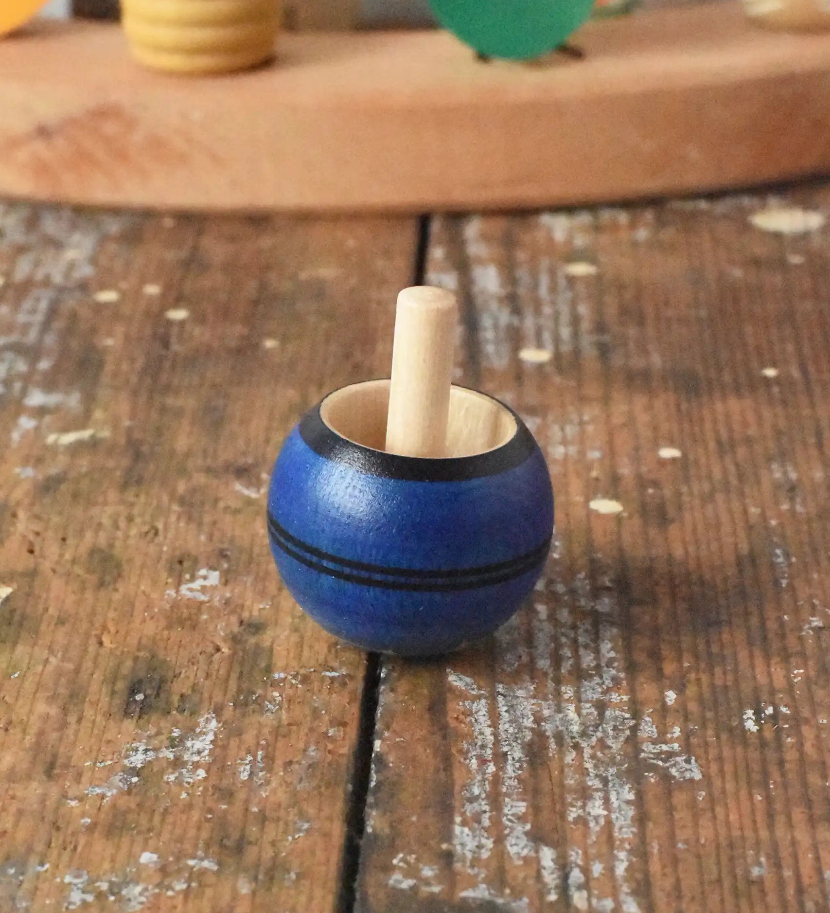 Mader Luna turn over spinning top shown on a wooden desk in the Babipur playroom.