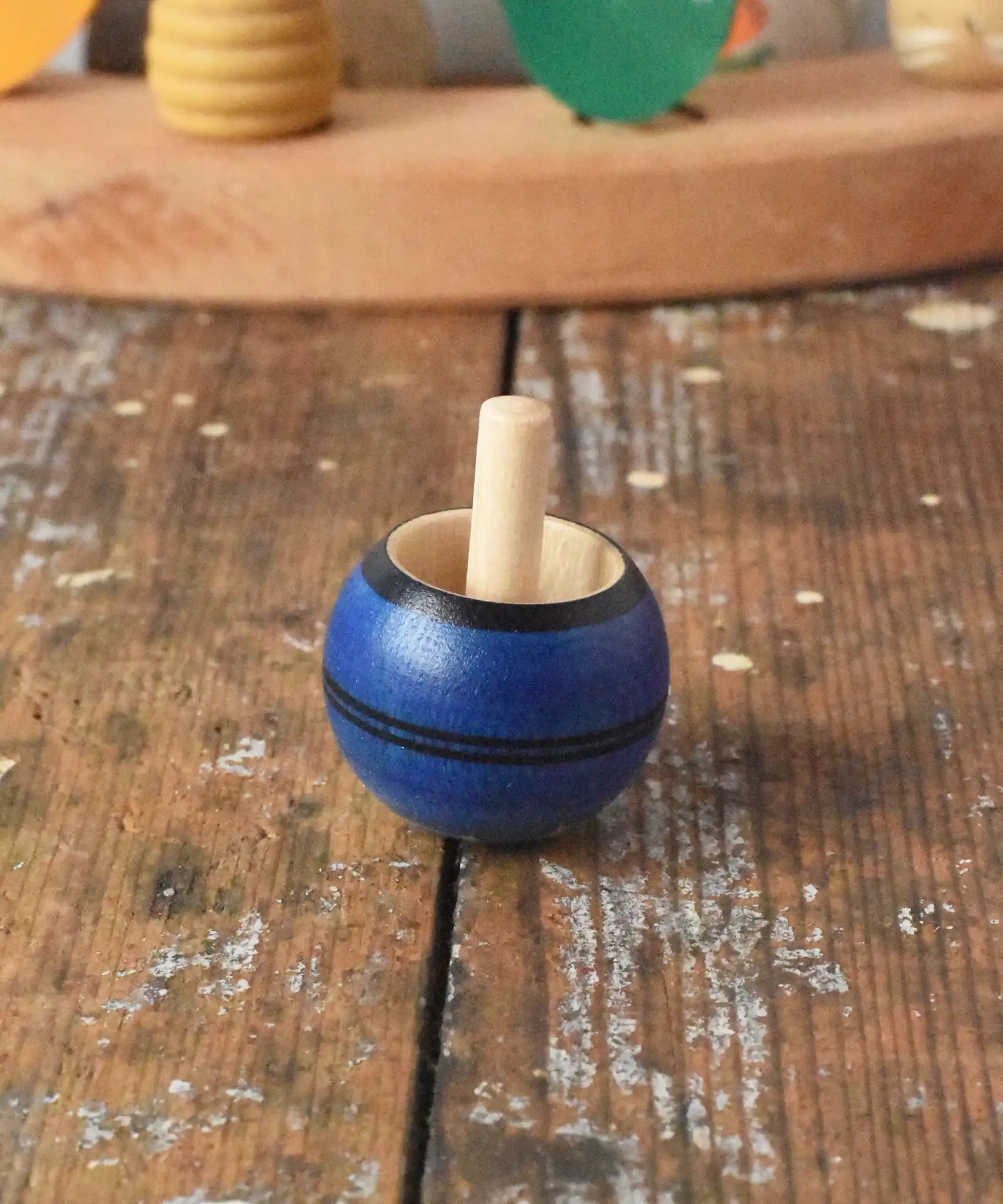 Mader Luna turn over spinning top shown on a wooden desk in the Babipur playroom.