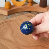 Close up of the stars and moon design on the Luna turn over top spinner, shown in an adult's hand in the Babipur playroom.