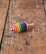 Mader handcrafted wooden rainbow mini thunderbolt spinning top placed on a wooden surface in the Babipur playroom. 