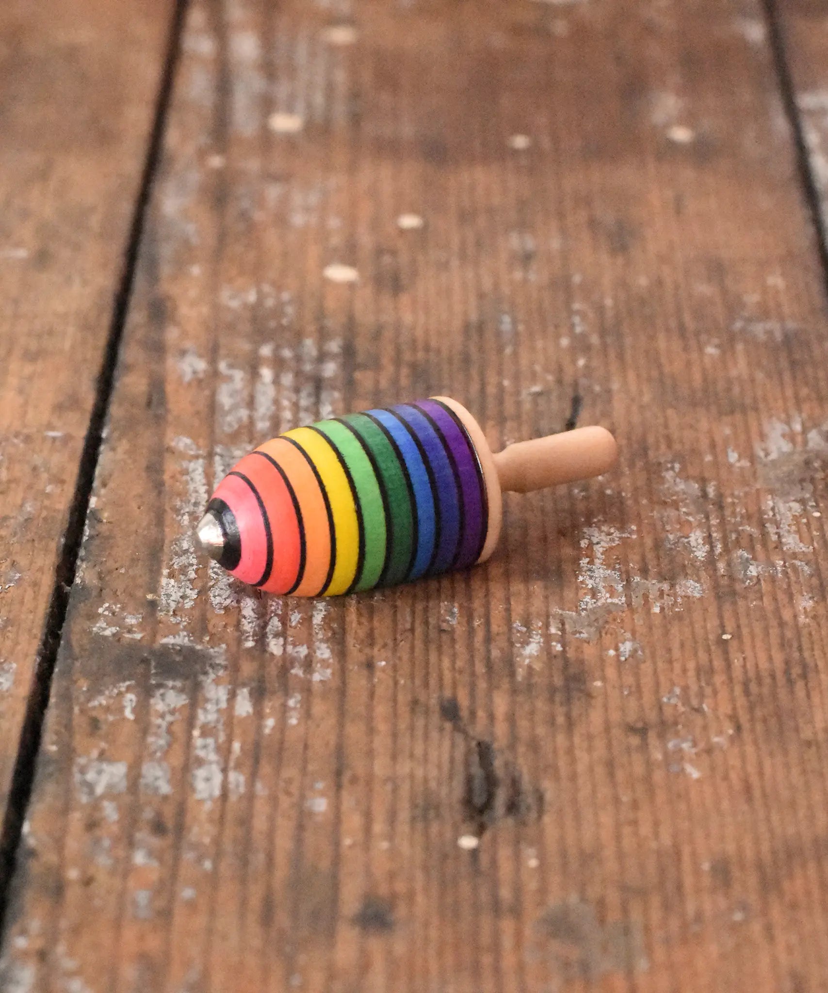 Mader handcrafted wooden rainbow mini thunderbolt spinning top placed on a wooden surface in the Babipur playroom. 