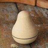 Mader Kreiselmanufaktur maple wood roly-poly pear wooden toy placed on a wooden surface in the Babipur playroom. 