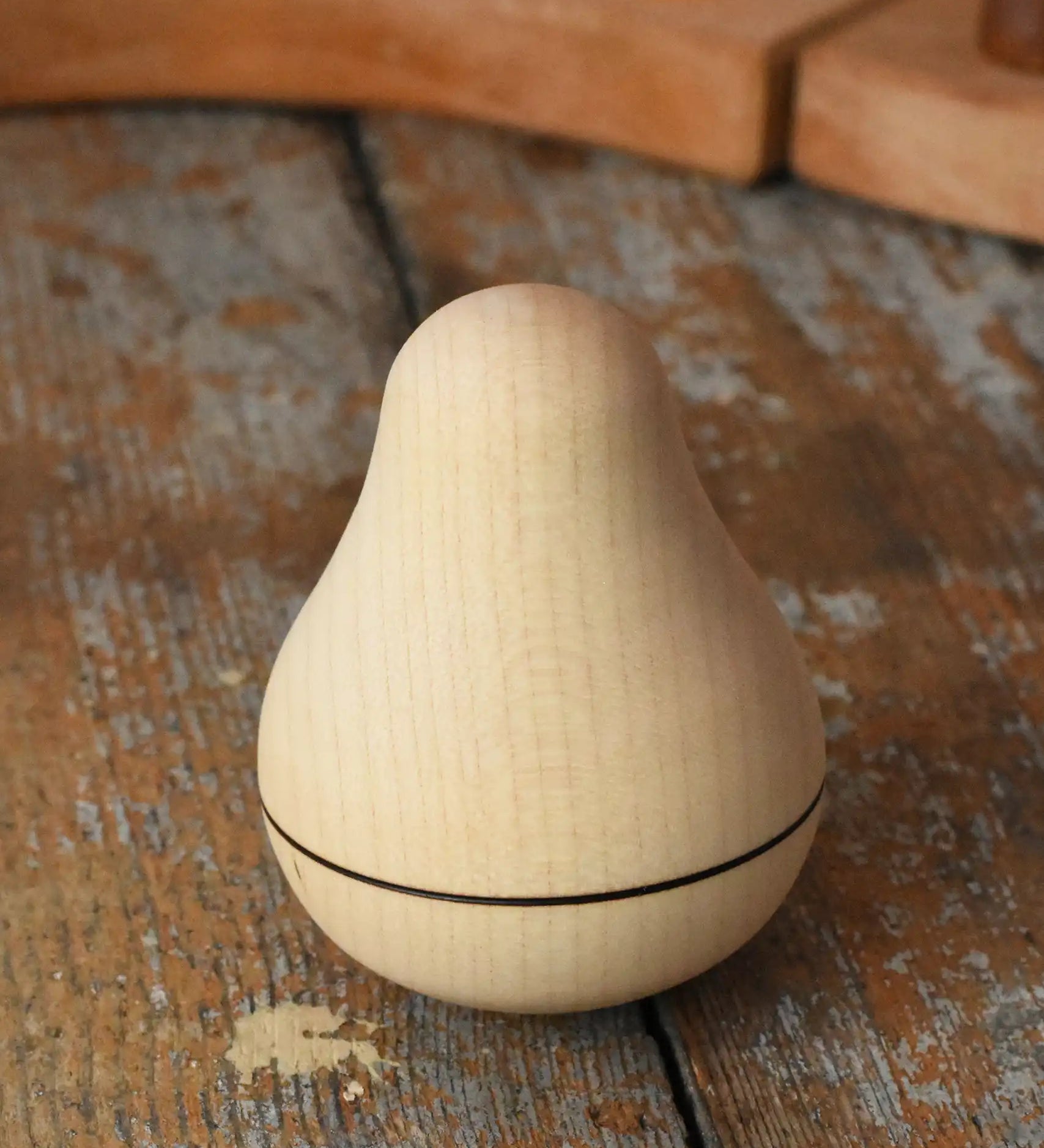 Mader Kreiselmanufaktur maple wood roly-poly pear wooden toy placed on a wooden surface in the Babipur playroom. 