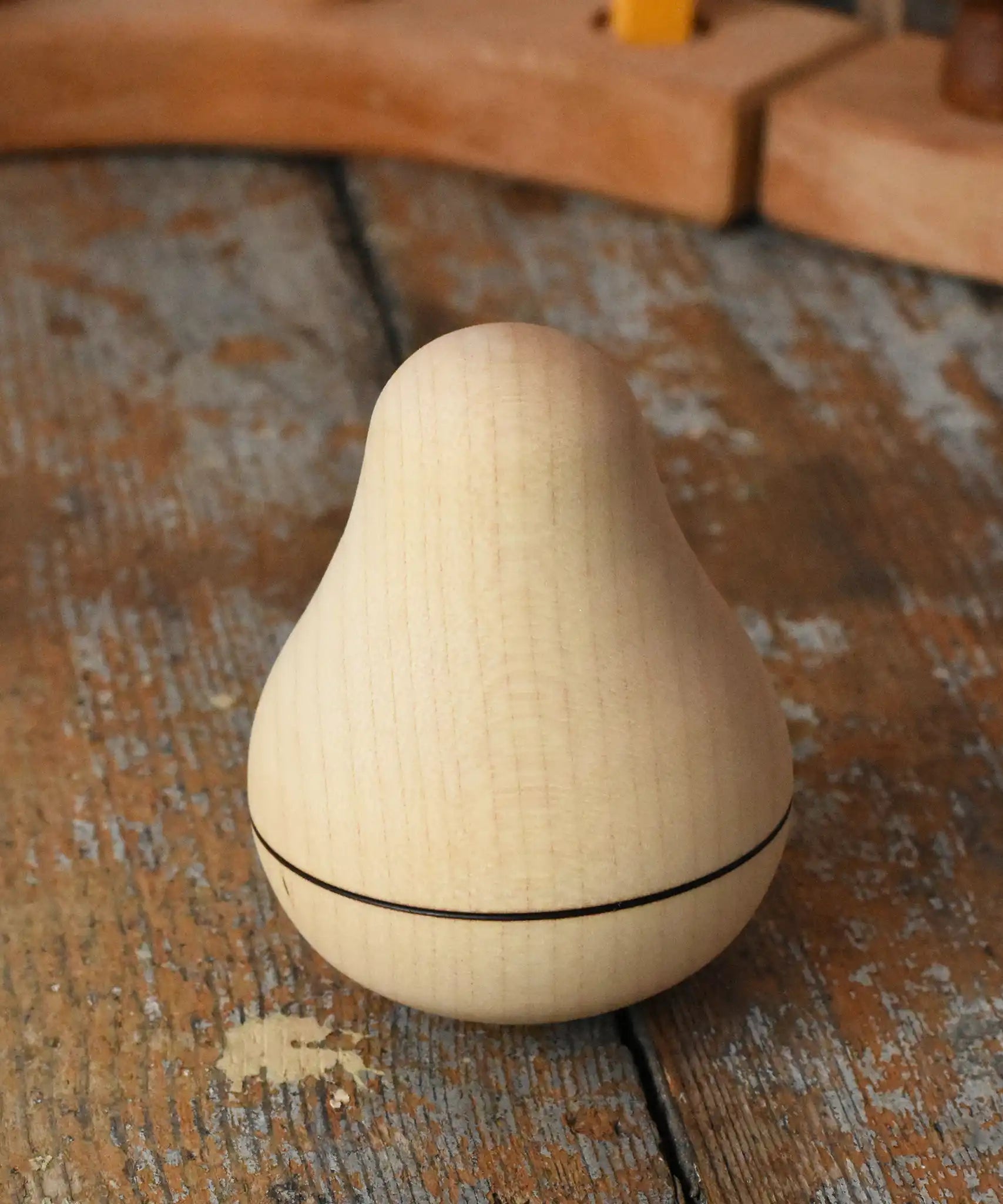 Mader Kreiselmanufaktur maple wood roly-poly pear wooden toy placed on a wooden surface in the Babipur playroom. 