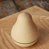 Mader Kreiselmanufaktur maple wood roly-poly pear wooden toy placed on an ash spinning plate on a wooden surface in the Babipur playroom. 