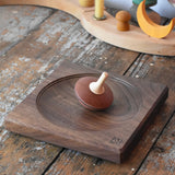 Mader walnut medium wooden spinning plate 15cm placed on a wooden surface in the Babipur playroom with  a nonna spinning top placed on it.