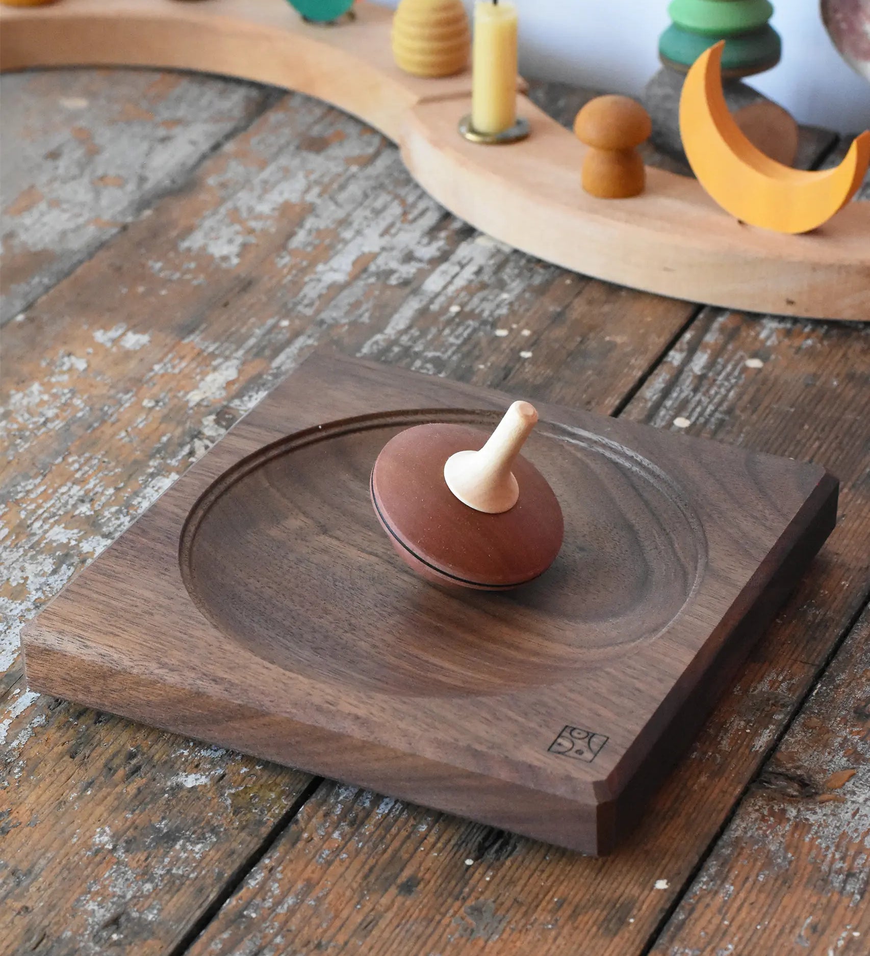 Mader walnut medium wooden spinning plate 15cm placed on a wooden surface in the Babipur playroom with  a nonna spinning top placed on it.