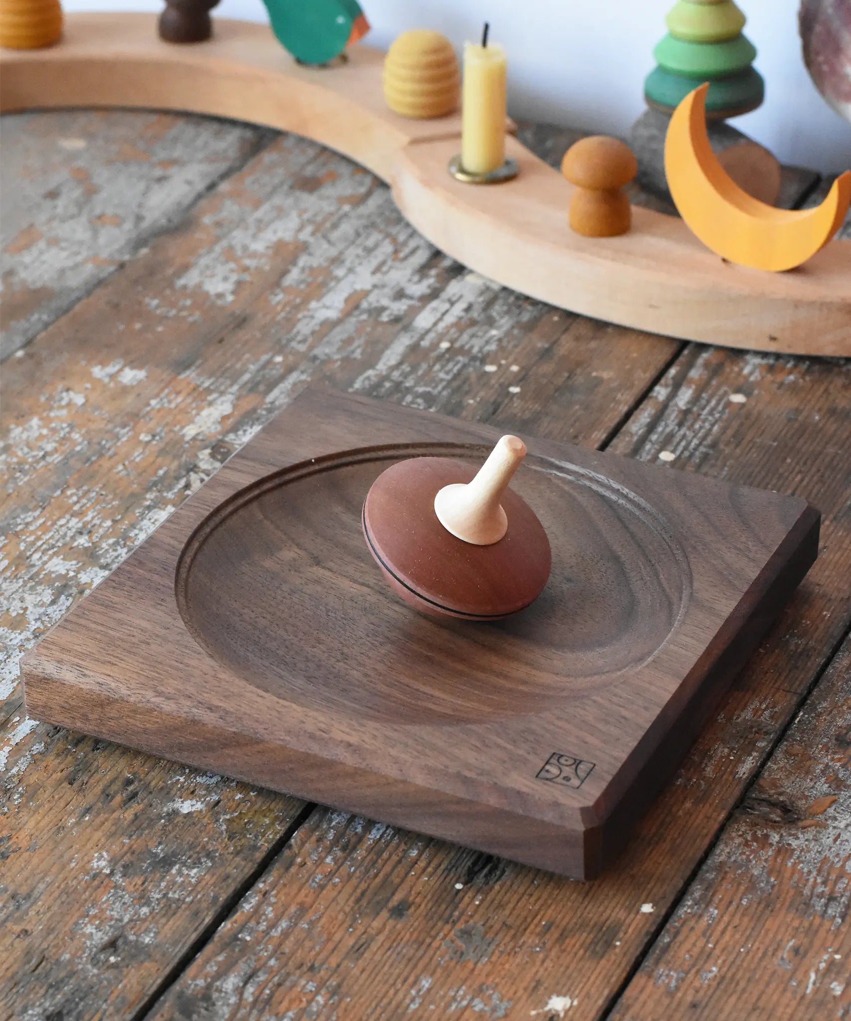 Mader walnut medium wooden spinning plate 15cm placed on a wooden surface in the Babipur playroom with  a nonna spinning top placed on it.