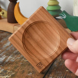 Mini wooden spinning plate board in an adult's hand in the Babipur playroom.