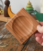 Mini wooden spinning plate board in an adult's hand in the Babipur playroom.