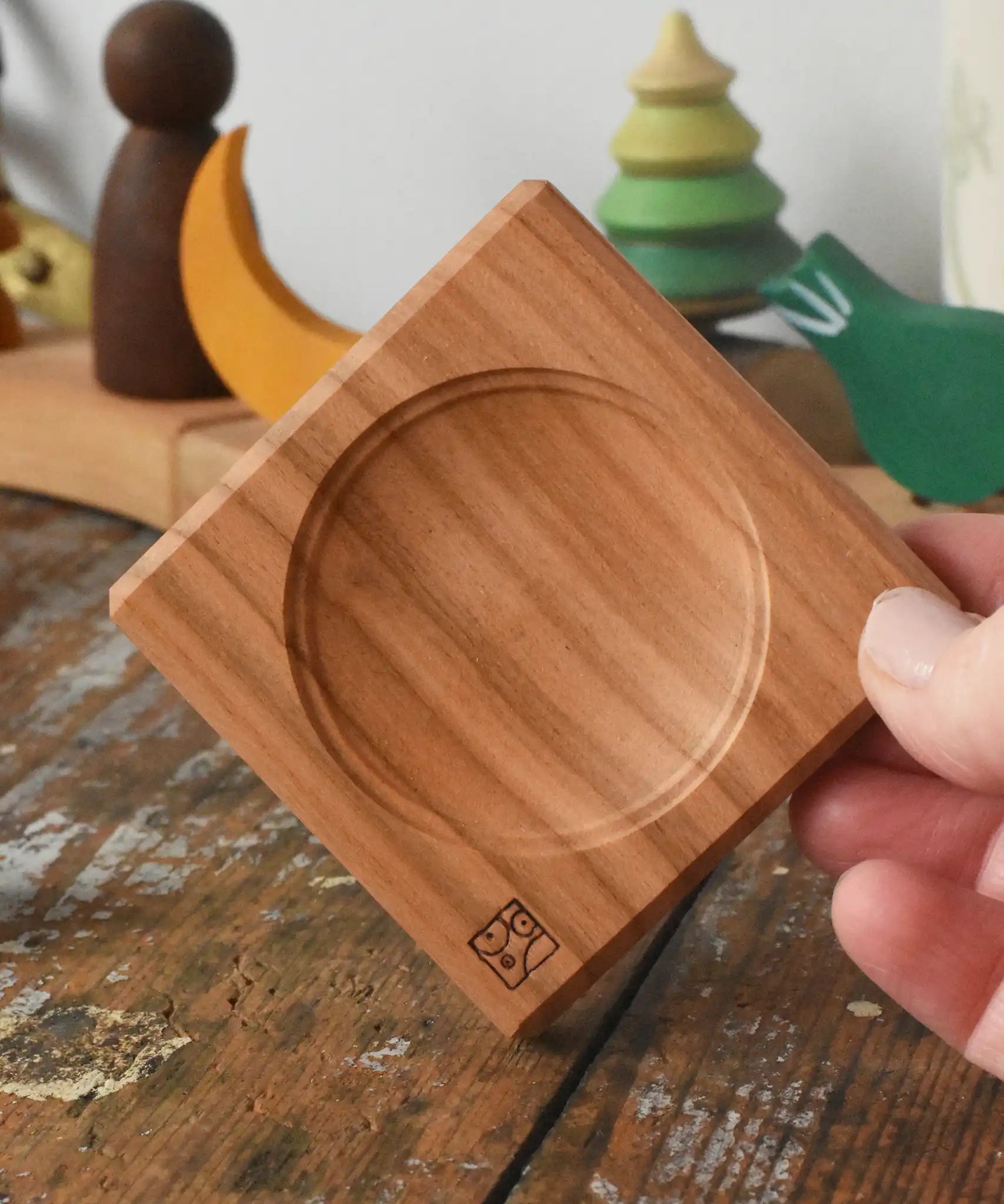 Mini wooden spinning plate board in an adult's hand in the Babipur playroom.