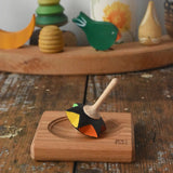 Mader Kreiselmanufaktur superstar wooden spinning top toy with and spinning plate placed on a wooden desk in the Babipur playroom.