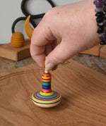 Mader Monalotte Spinning Top being placed on a oak spinning plate in the Babipur playroom.