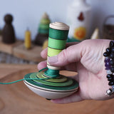 Mader wooden my first spinning top toy with starter in greenin an adult's hand in the Babipur playroom.