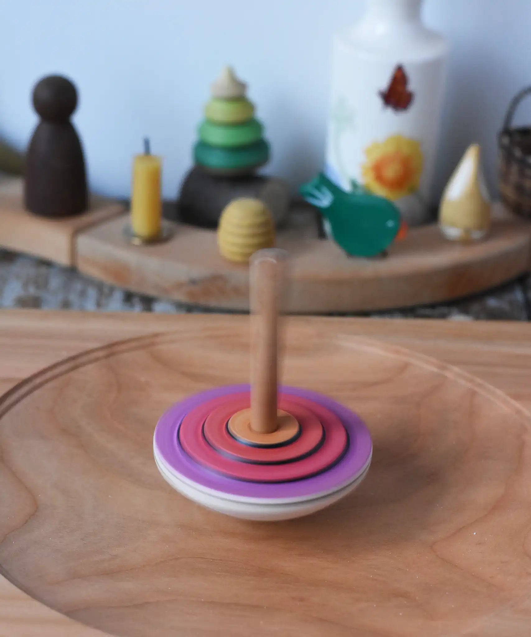Mader my first spinning top toy with starter in pink spinning in motion on a large cherry wood spinning plate in the Babipur playroom. 