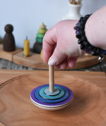 Mader my first spinning top toy in purple placed on a large cherry wood  spinning plate in the Babipur playroom. 