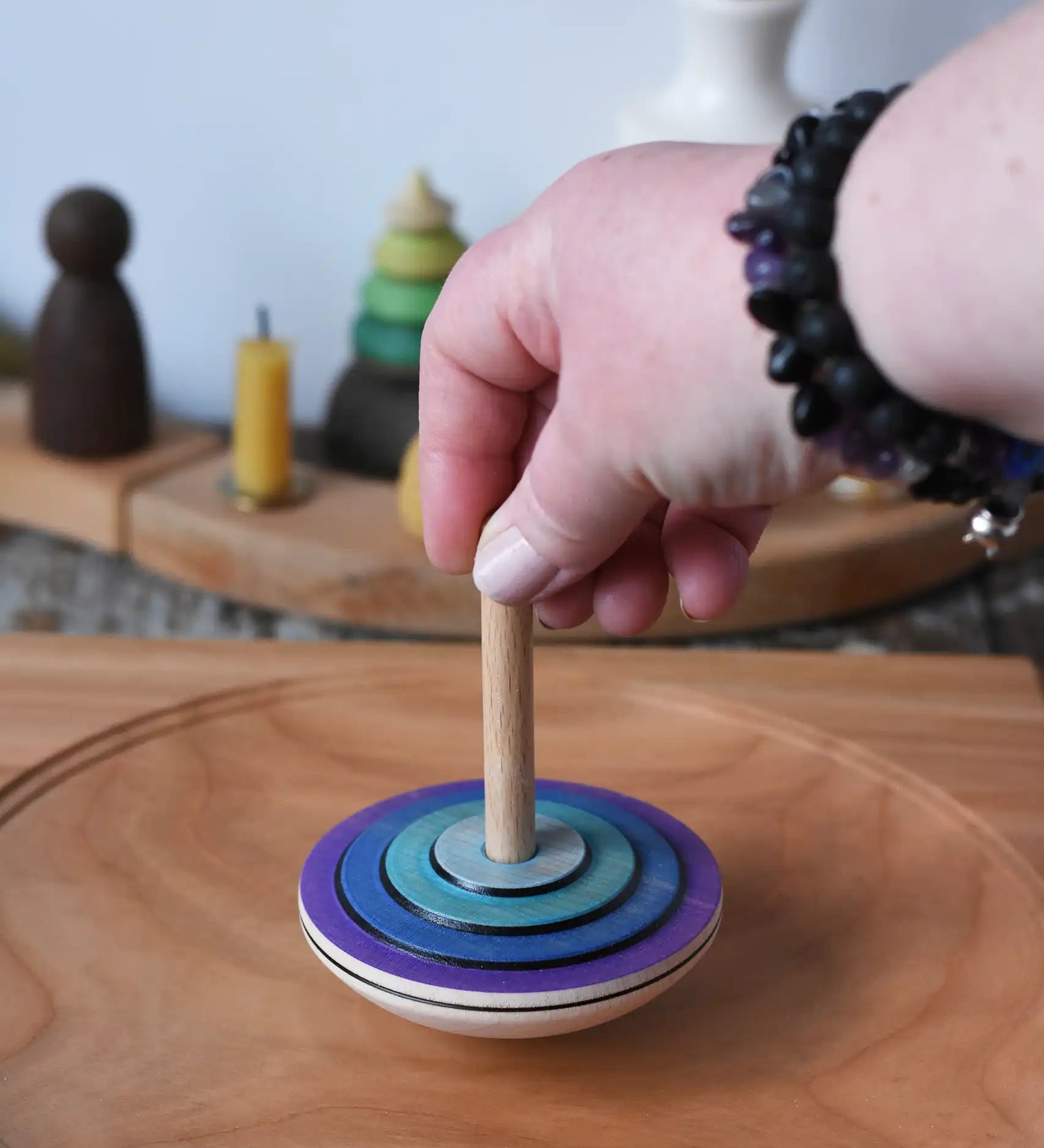 Mader my first spinning top toy in purple placed on a large cherry wood  spinning plate in the Babipur playroom. 