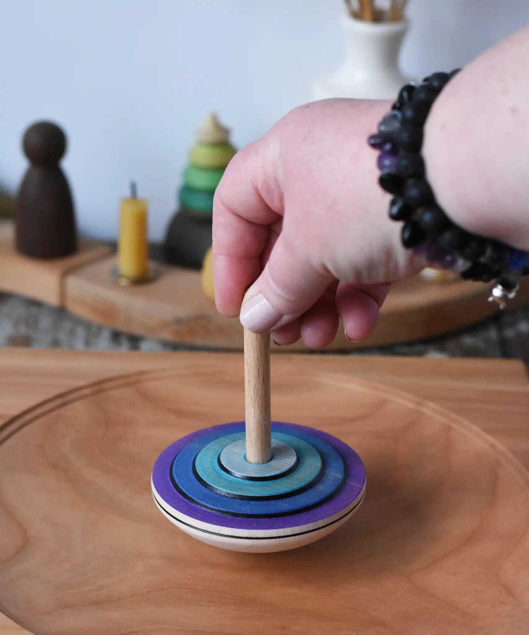 Mader my first spinning top toy in purple placed on a large cherry wood  spinning plate in the Babipur playroom. 