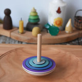 Close up of the Mader my first spinning top toy in purple spiining in motion on a large cherry wood spinning plate in the Babipur playroom. 