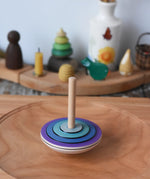 Close up of the Mader my first spinning top toy in purple spiining in motion on a large cherry wood spinning plate in the Babipur playroom. 