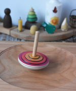 Mader wooden my first spinning top toy with starter in red spinning in motion on a spinning plate in the Babipur playroom.