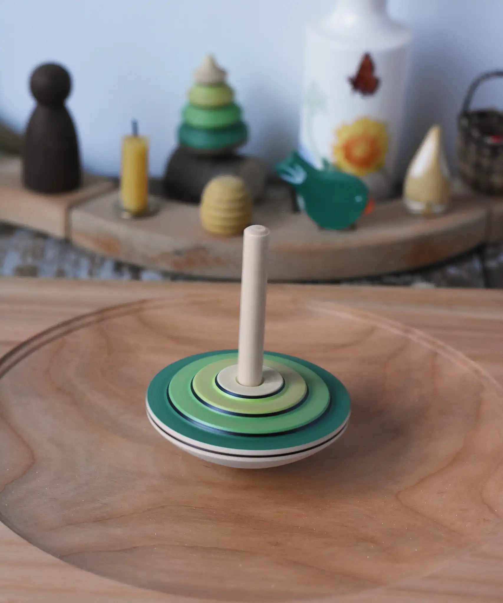 Mader wooden my first spinning top toy with starter in green spinning in motion on a large cherry wood spinning plate in the Babipur playroom.