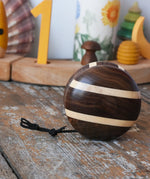 Mader natural yoyo placed on a wooden surface in the Babipur playroom. Decorated Grimm's celebration ring in the background. 