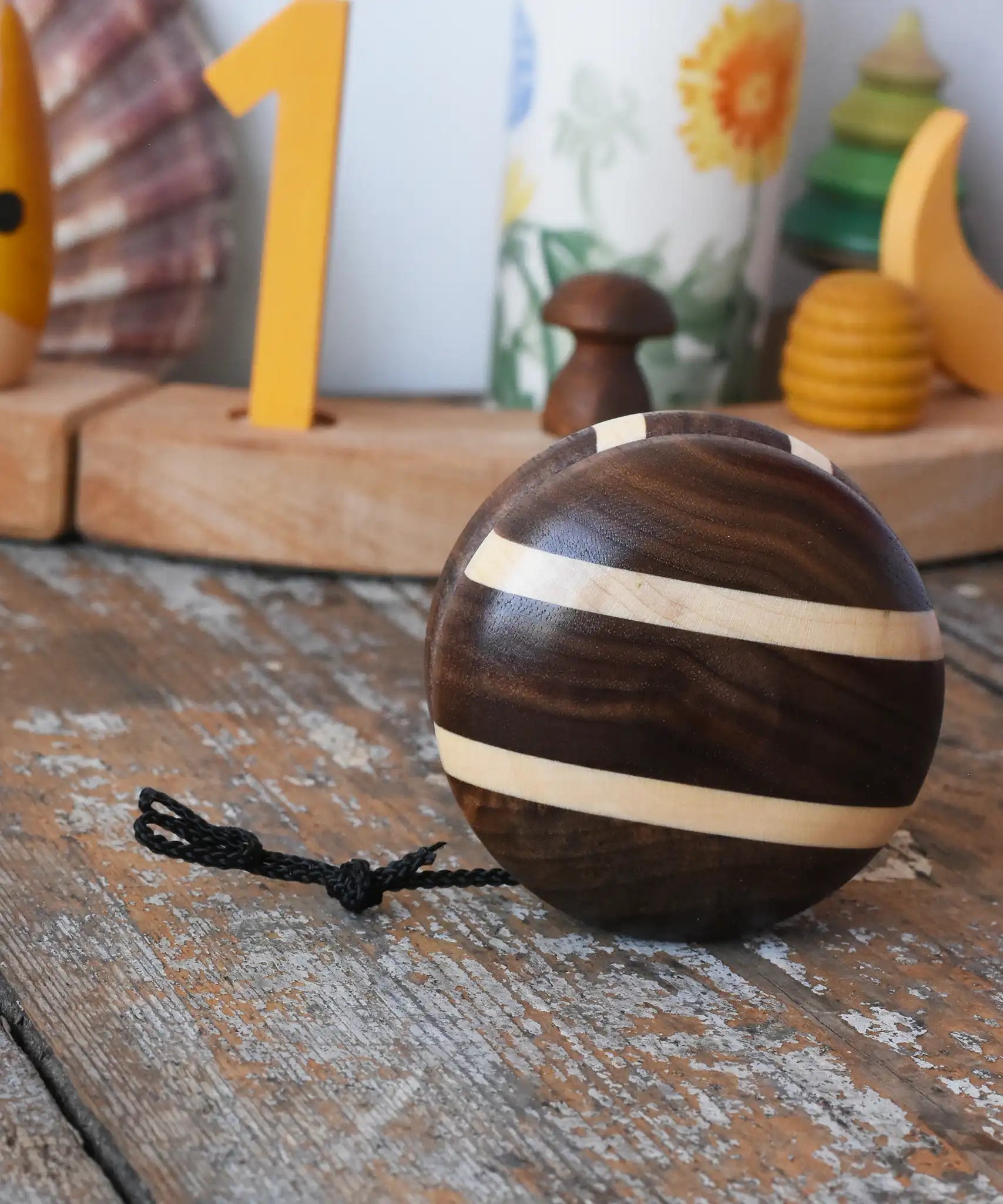 Mader natural yoyo placed on a wooden surface in the Babipur playroom. Decorated Grimm's celebration ring in the background. 